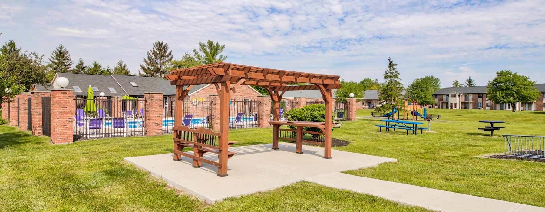 Outdoor pergola with seating near a playground